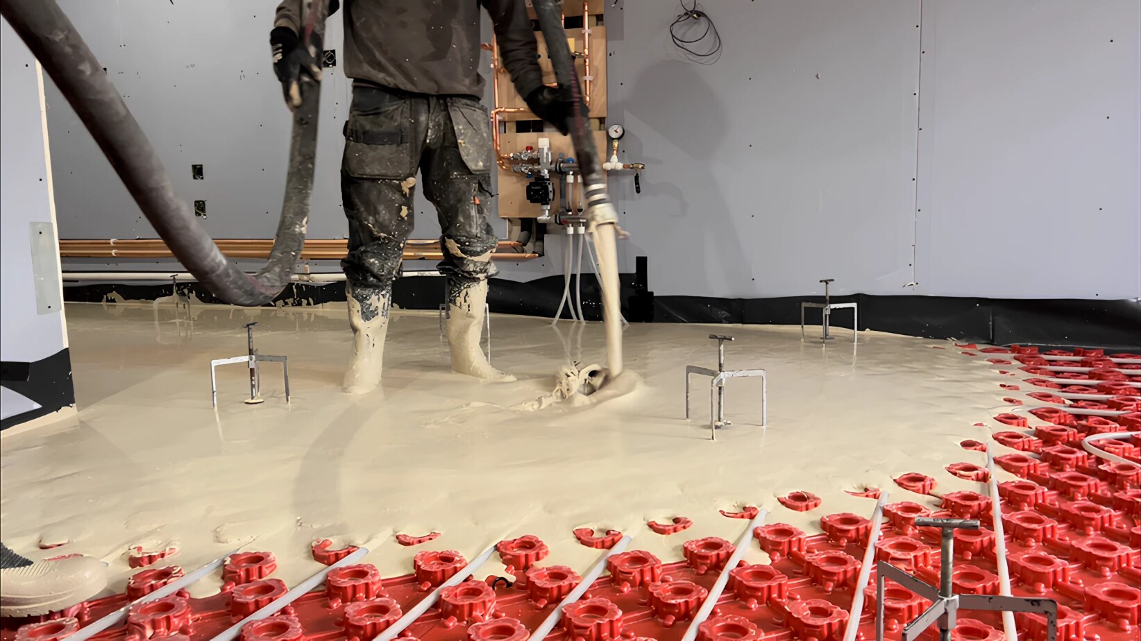 A J & H Lynch operative pumping liquid screed over underfloor heating pipes